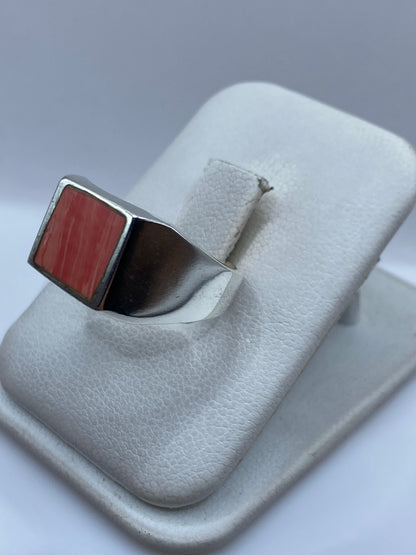 Anillo de coral en plata, llevado en dedo, mostrando el diseño geométrico y el brillo espejo