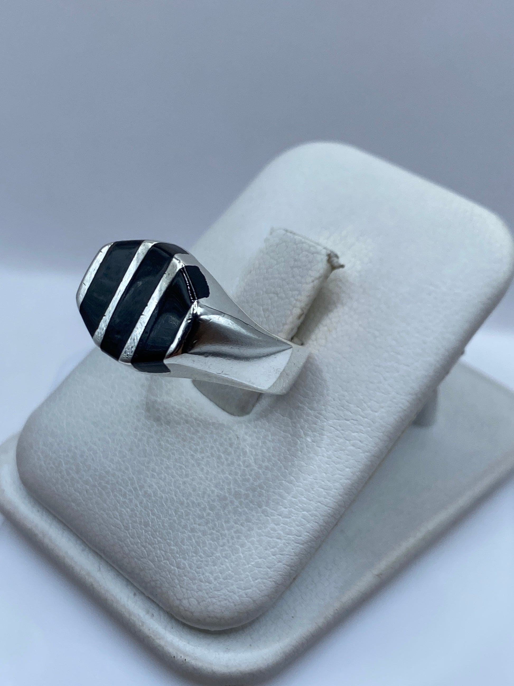 Anillo en la mano mostrando el ónix negro pulido y la plata brillante