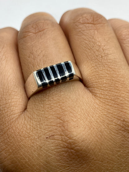 Anillo sobre fondo neutro, demostrando el contraste entre plata pulida y ónix negro