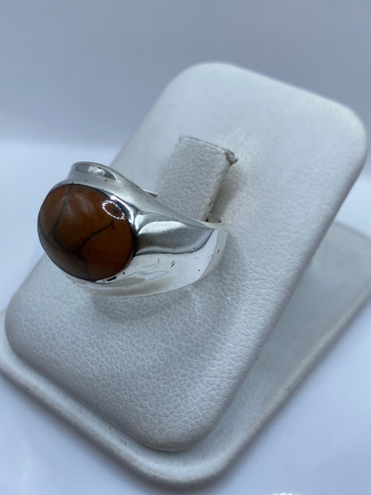 Detalle lateral del anillo mostrando el engaste a mano de la piedra café