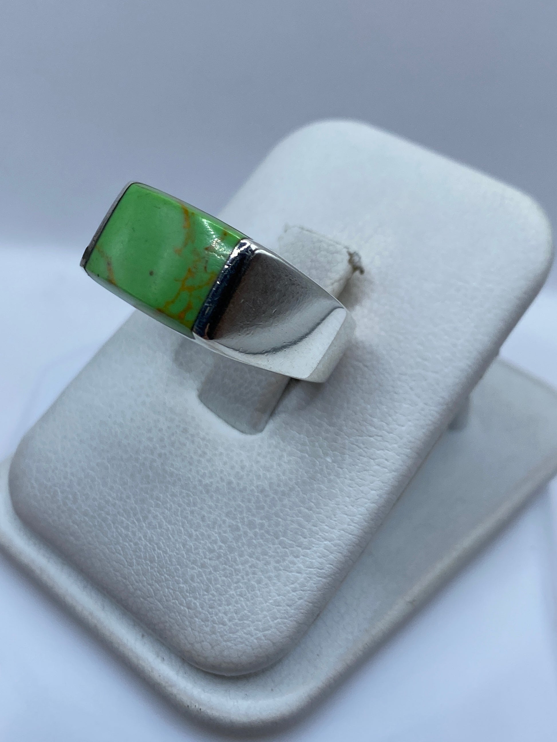 Detalle lateral del anillo mostrando el engaste de la piedra verde en la plata