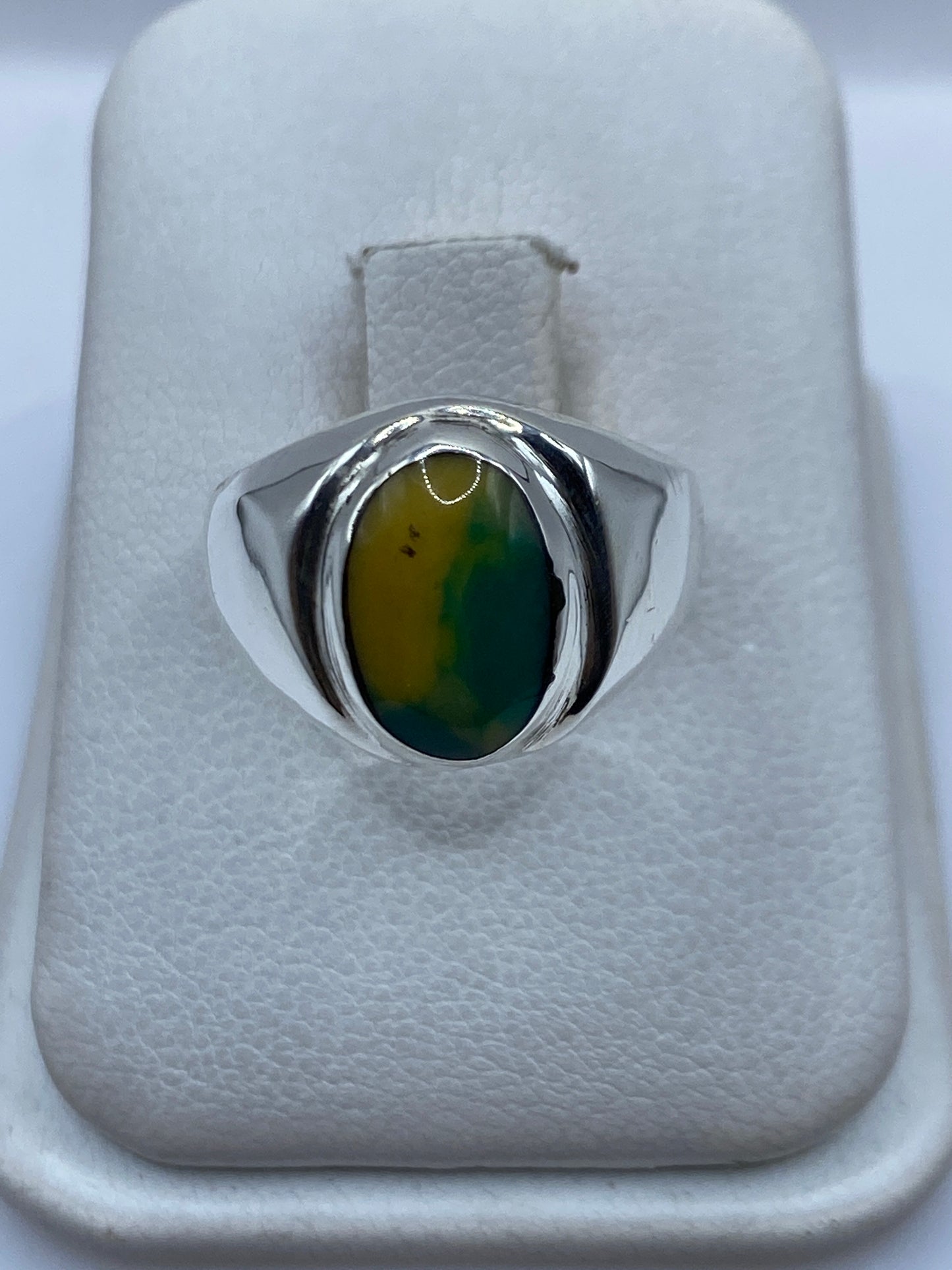 Anillo de plata .925 con piedra amarilla engastada, vista frontal sobre cojín blanco