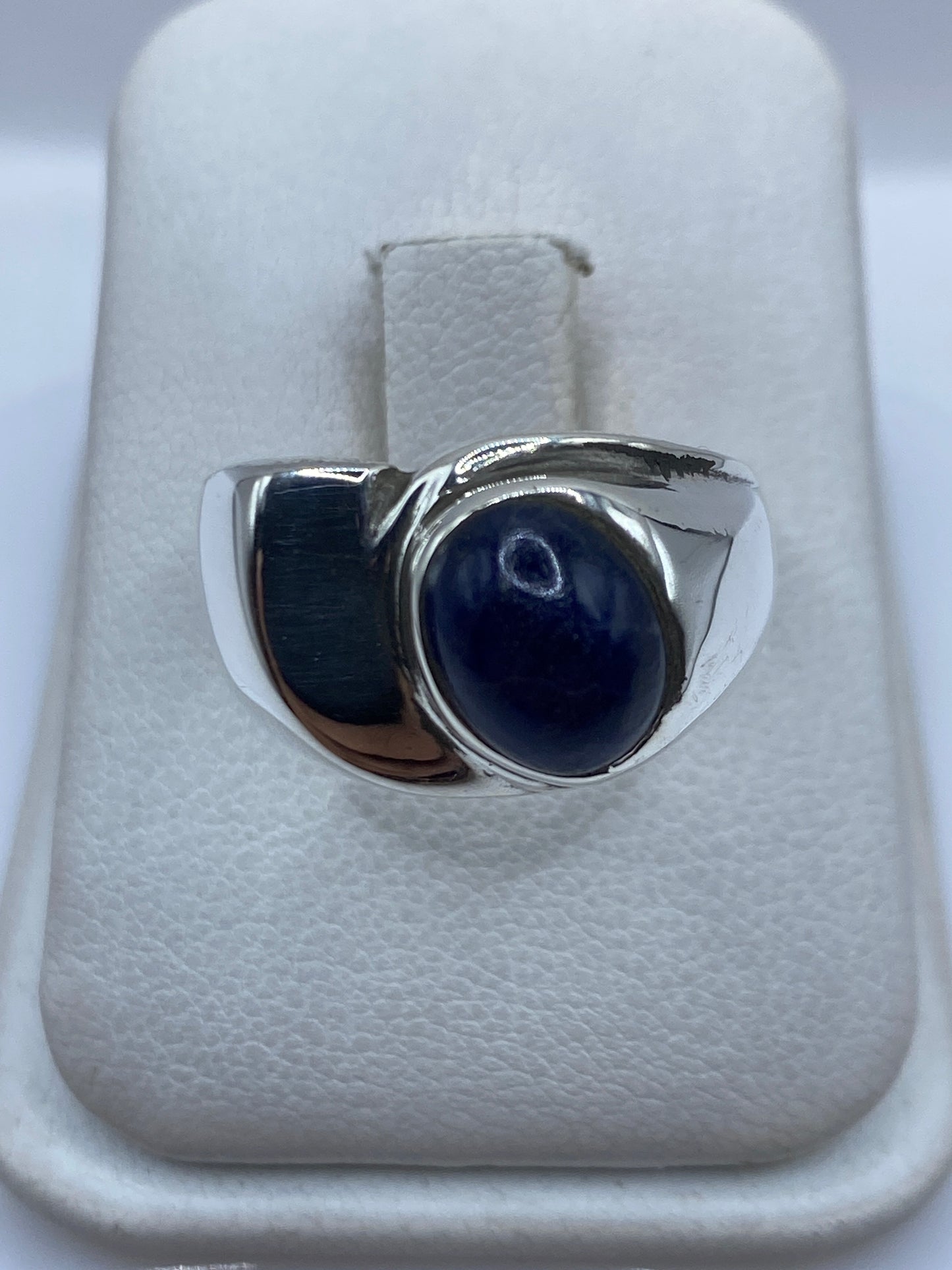 Anillo de plata con piedra azul engastada sobre estuche blanco de presentación