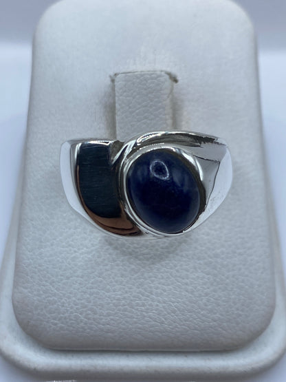 Anillo de plata con piedra azul engastada sobre estuche blanco de presentación