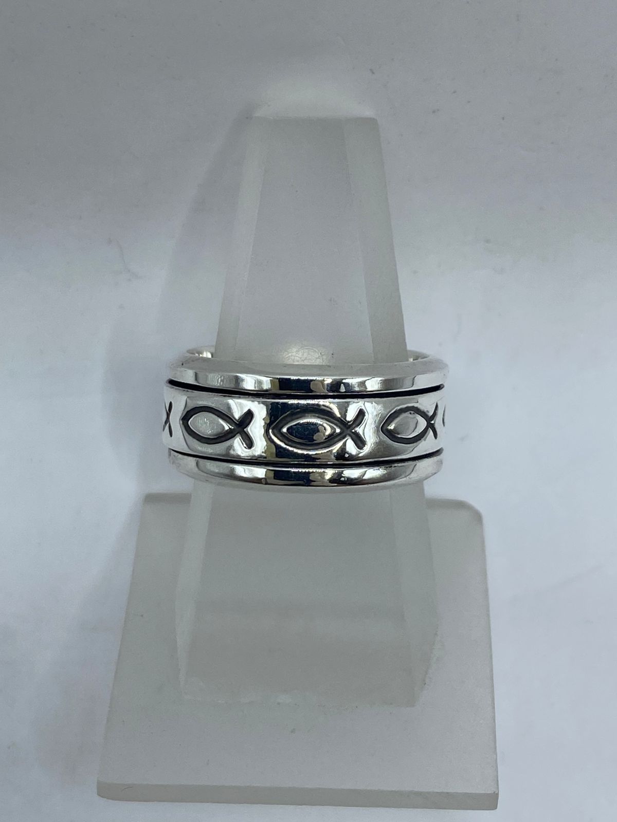 Vista frontal de anillo spinner plata .925 con pez ictus cristiano en banda giratoria sobre fondo oxidado — artesanal Taxco
